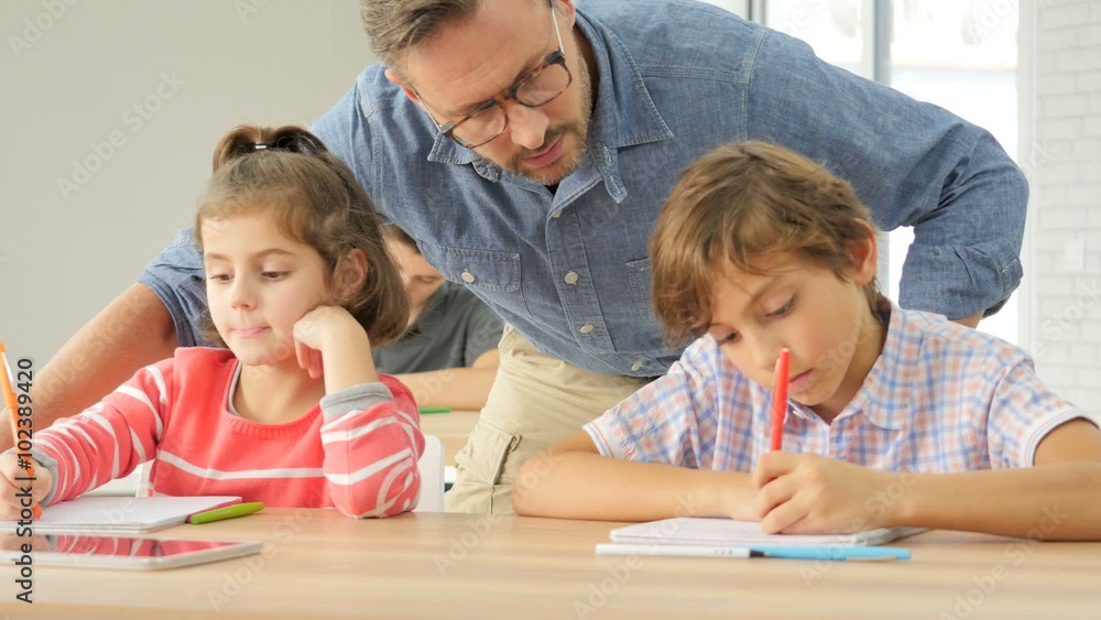 Teacher helping pupils with writing lesson Teacher helping pupils with writing lesson