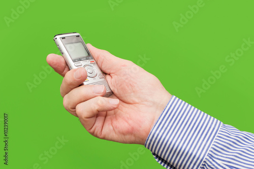 Canvas-taulu Elderly man is holding voice recorder on green background, color and contrast ma