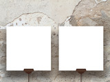 Close-up of two hanged square paper sheet frames on weathered cracked wall background