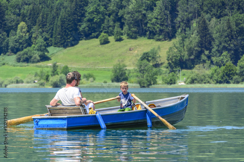 kleiner Junge rudert mit den Eltern über den See