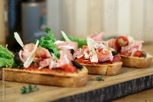 Slices of prosciutto rolled up and arranged on a lettuce leaf.