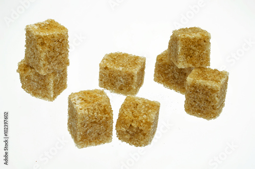 einige braune Zuckerwuerfel auf weissem Hintergrund photo