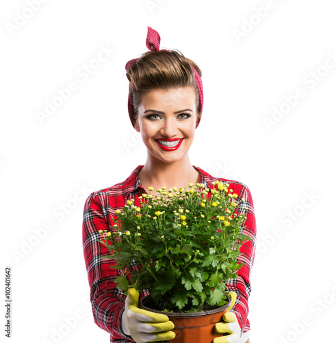 Woman with pin-up hairstyle holding flower pot with yellow daisi photo