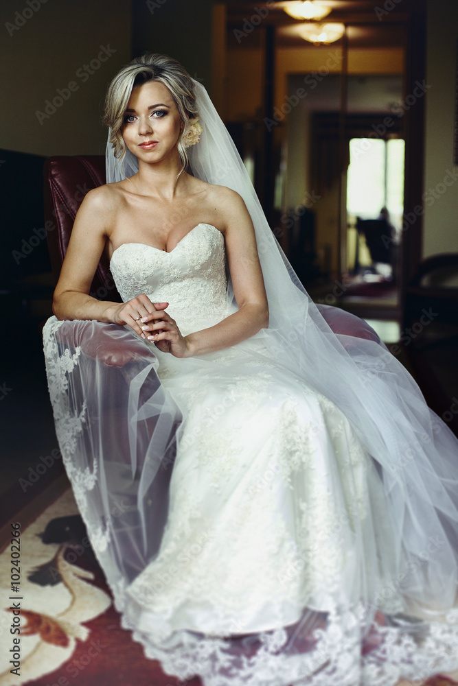 Naklejka premium Beautiful, stylish blonde bride posing on leather chair