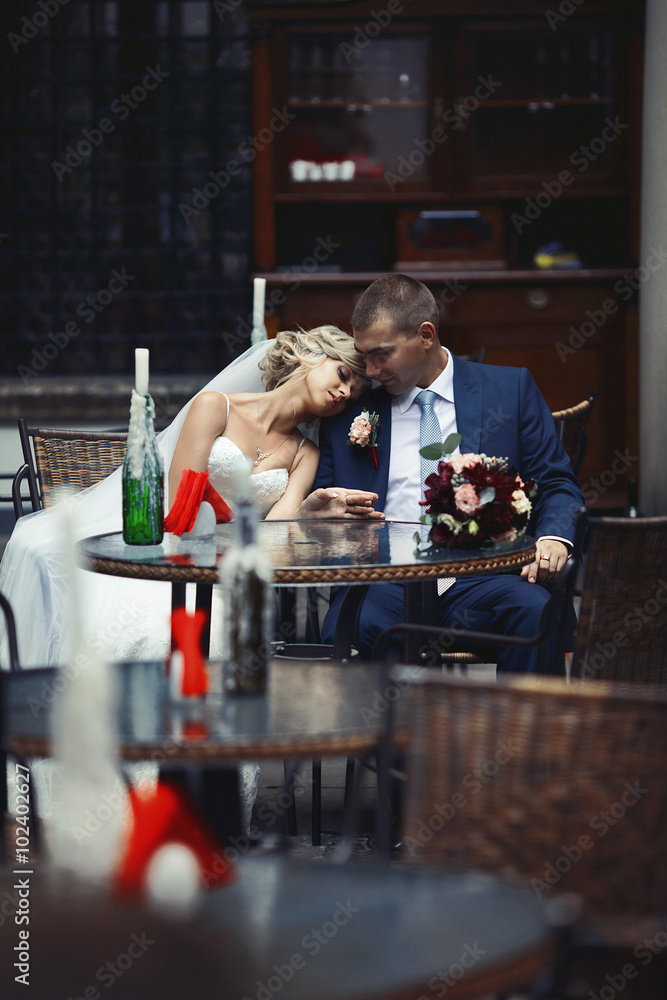 Romantic relaxed newlywed couple sitting at restaurant table