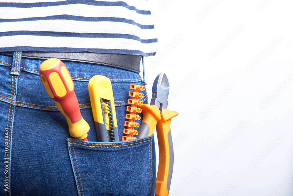 Tools for electrician in back pocket of blue jeans worn by a woman.  Screwdriver, sharp knife, cutters and connectors. Stock Photo | Adobe Stock