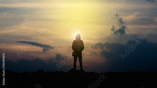 The silhouette of a man holding a camera watching the sunset.