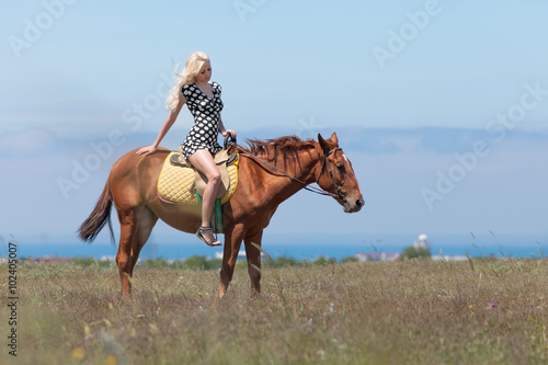 Girl in polka-dot dress rides on horse