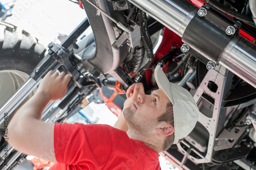 Young repairman ( farmer )  repairs tractor