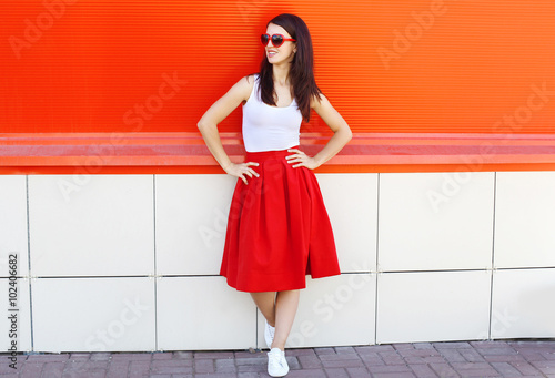 Beautiful brunette woman wearing a sunglasses and red skirt in c
