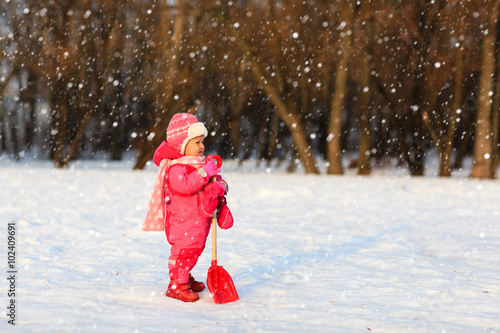 cute little toddler girl dig in winter snow