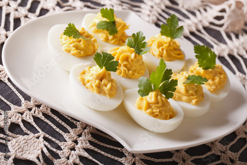 Delicious stuffed eggs close-up on a plate on the table. Horizontal 