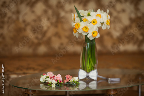 White narcissus flowers in vase, bowtie and boutonnieres on tabl photo