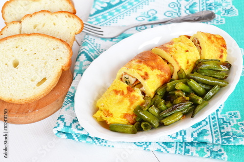 Rolls of omelette with cheese on a plate, 
fried green beans