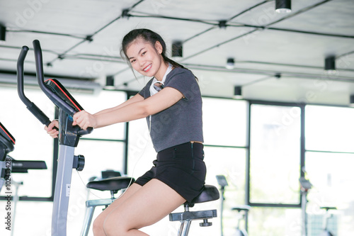 Asian woman exercising at the gym on a cross trainer