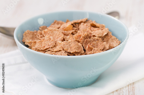 cereals in blue bowl on white wooden background