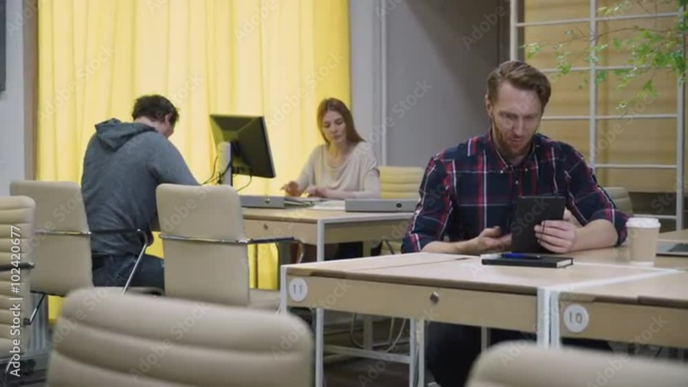 A bearded man talking on a tablet in the eco office A bearded man talking on a tablet in the eco office
