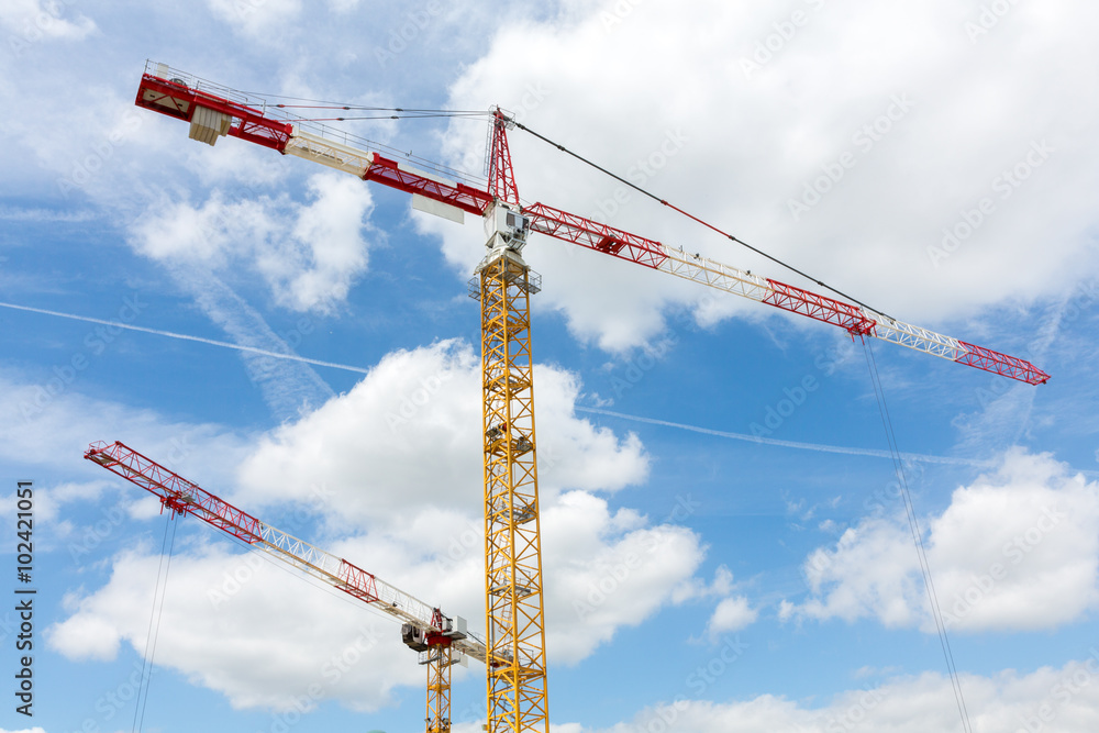 2 tower cranes on cloud and blue sky background 2 tower cranes on cloud and blue sky background