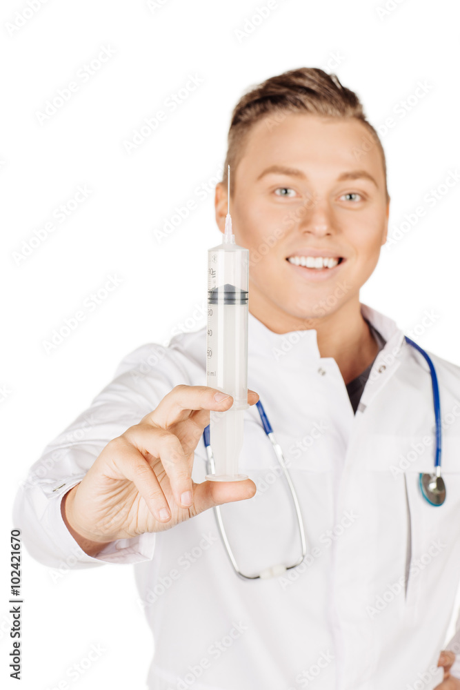 Young male doctor in white coat and stethoscope holding syringe. Young male doctor in white coat and stethoscope holding syringe.