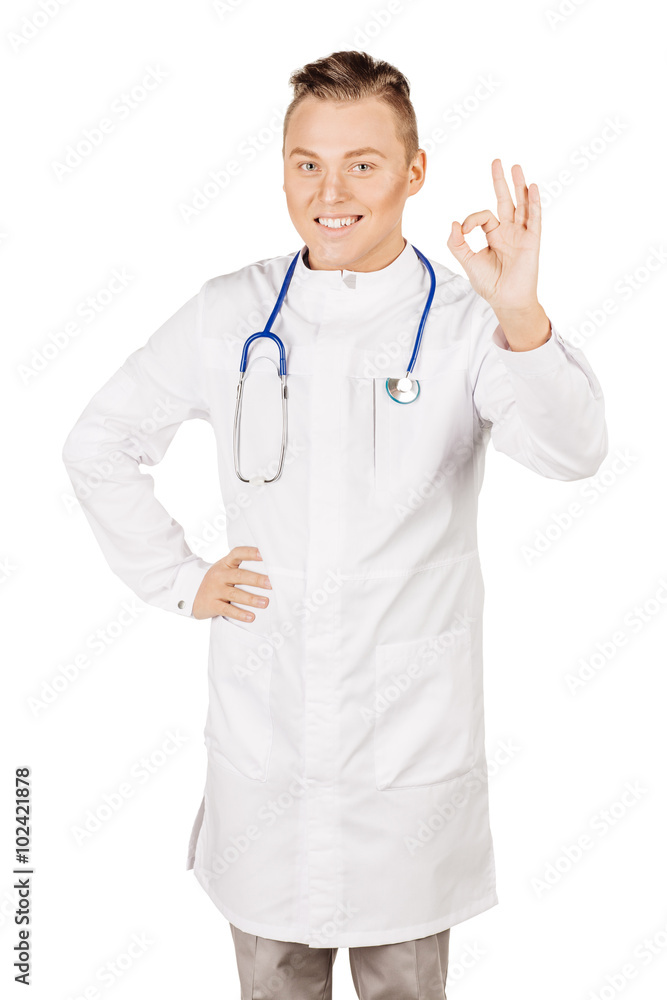 Young male doctor in white coat and stethoscope showing ok hand