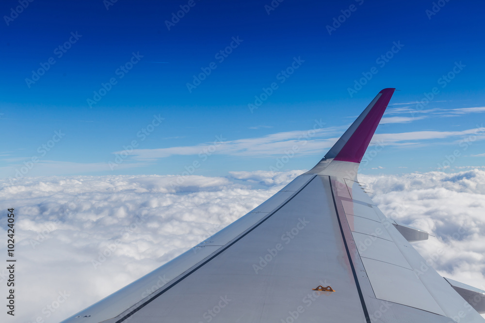 Blue horizon and white clouds. Aerial shot with airplane wing