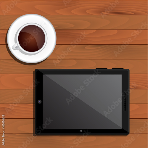 Black tablet and cup of coffee on table