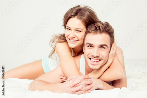 in honeymoon cheerful young couple in love embracing in the bedr