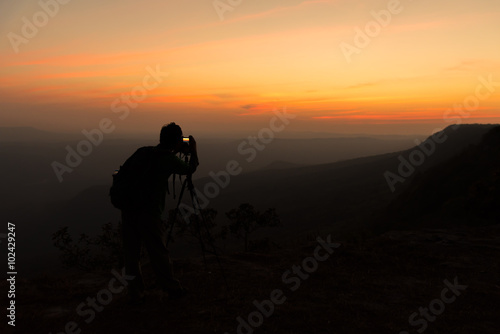 Silhouette of photographer when he is taking photograph on mountain
