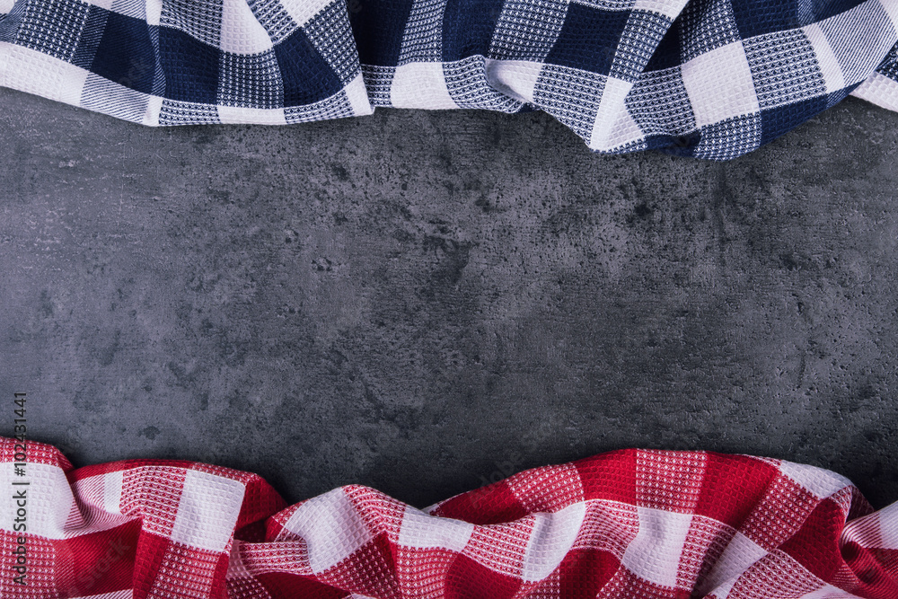 Obraz premium Top view of checkered kitchen tablecloth on granite - concrete - stone background. Free space for your text or products.