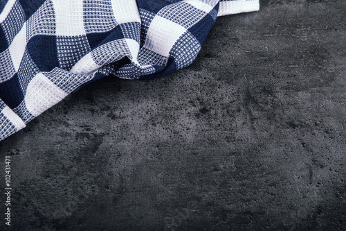 Top view of checkered kitchen tablecloth on granite - concrete - stone background. Free space for your text or products.