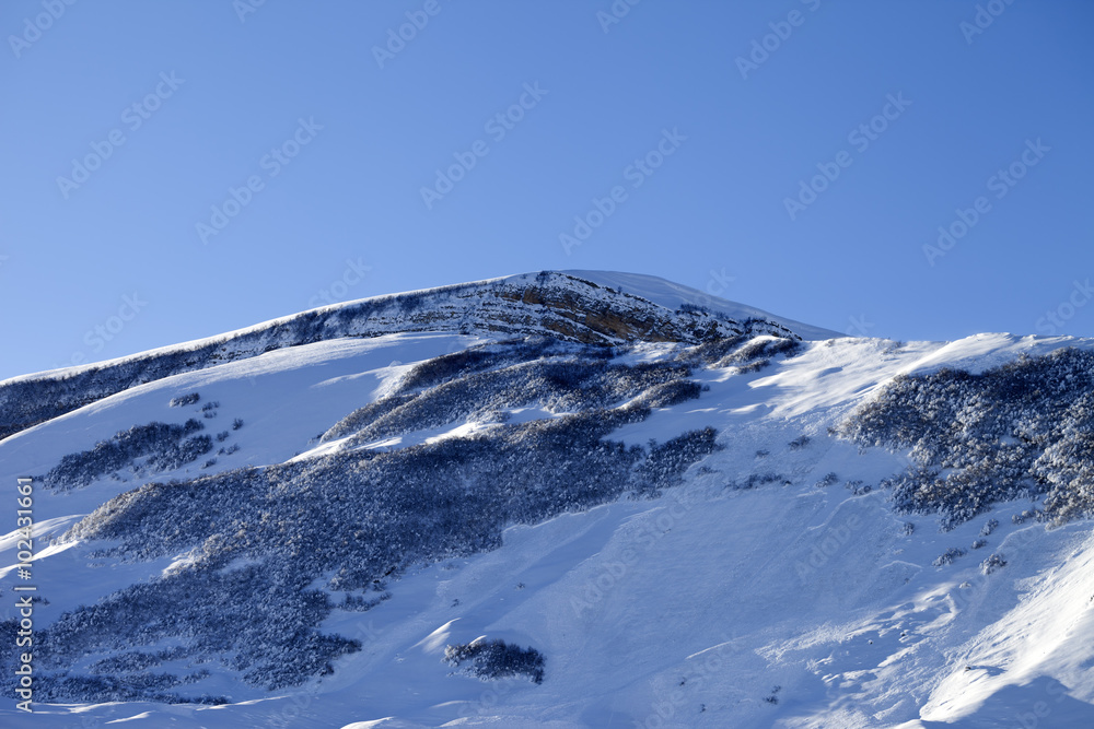 Snowy mountains with track from avalanche after snowfall