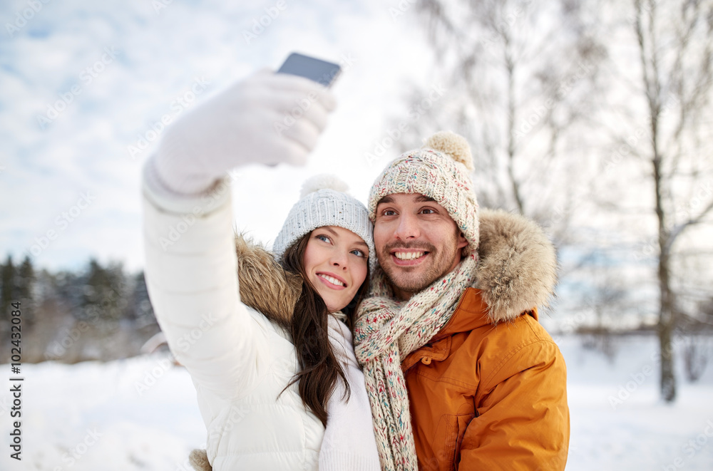 Fototapeta premium happy couple taking selfie by smartphone in winter