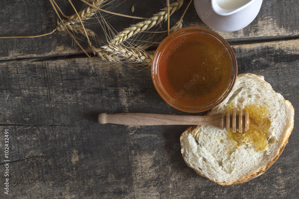Honey in a jar, bread, wheat and milk on wood table. Honey in a jar, bread, wheat and milk on wood table.