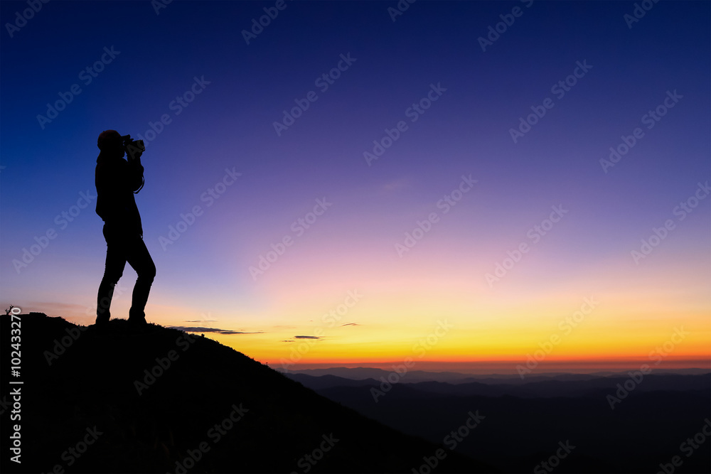 silhouette of woman taking photograph on the top of mountain and enjoy colourful sky