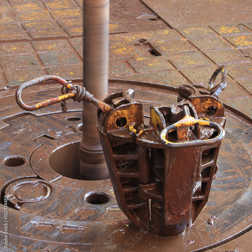 Slip on the rotary table while drilling oil well and pipe being rotated photo