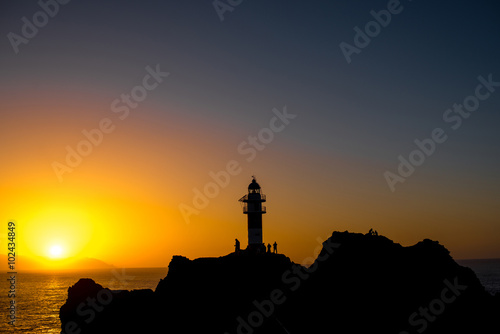 Rocky coastline with lighthouse on the sunset