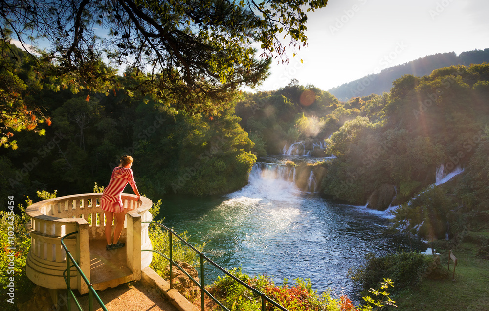 Naklejka premium Young woman looks over the waterfalls of the Krka river in Krka national park in Croatia