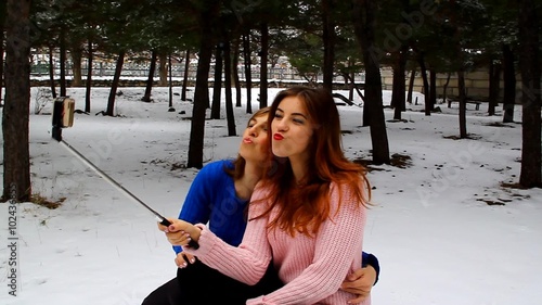 Mother and daughter take a picture of yourself in park on phone outdoors