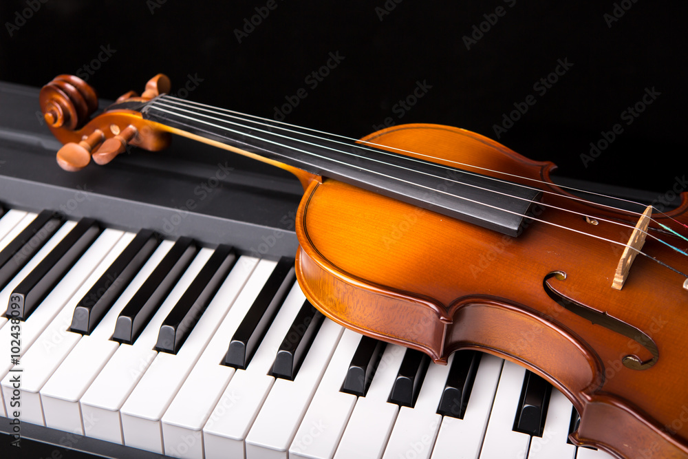 Fototapeta premium Violin on the piano on a black background