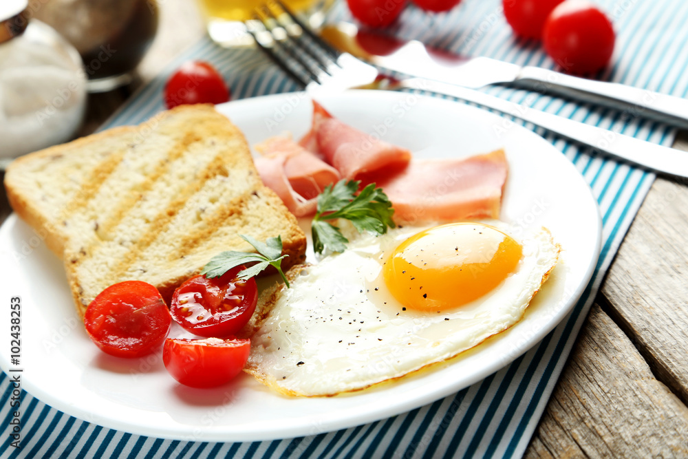 Fototapeta premium Fried eggs with bacon and toasts on plate on grey wooden table