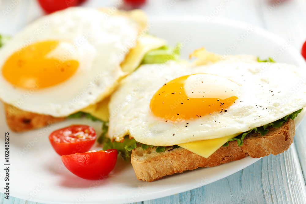 Fried eggs with toasts on plate on blue wooden table