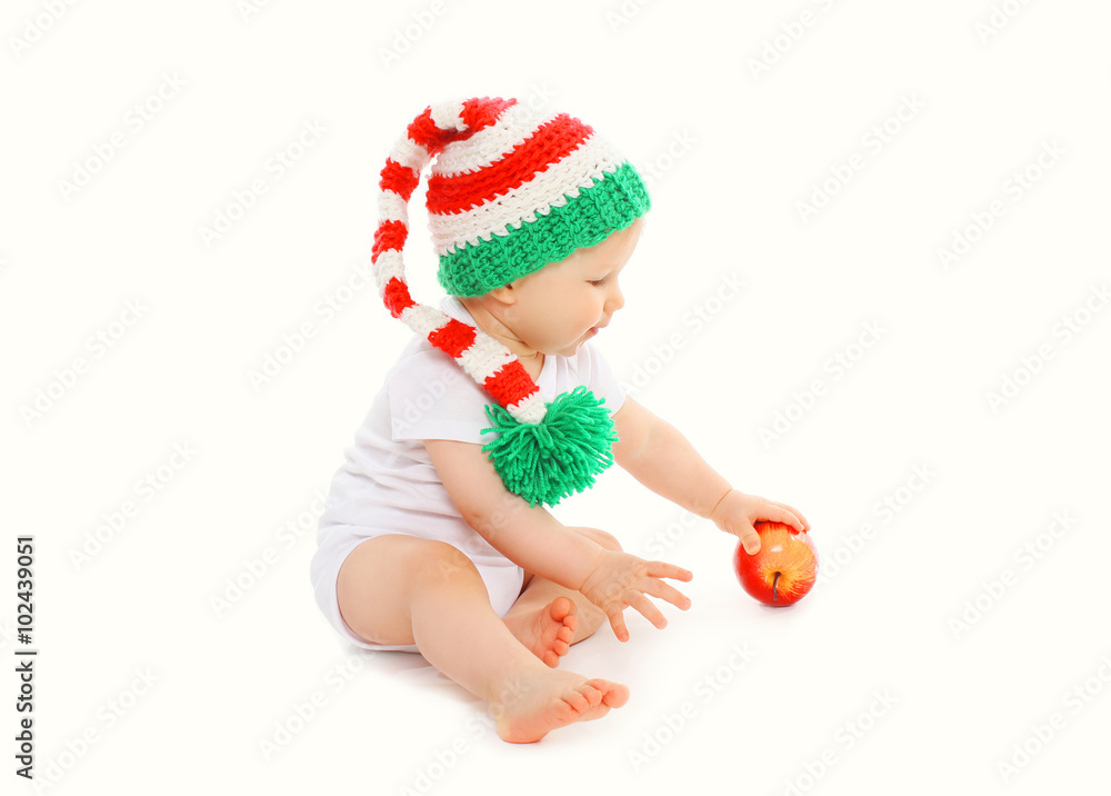 Baby in knitted hat with red apple on white background Baby in knitted hat with red apple on white background
