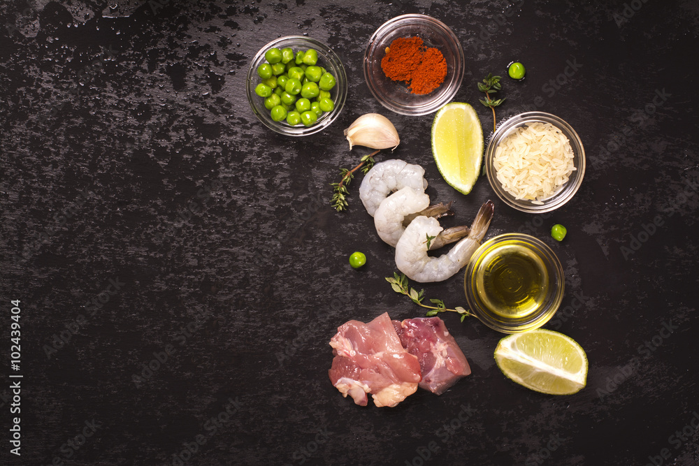 Spanish paella ingredients over black stone background. Top view. Toned image Spanish paella ingredients over black stone background. Top view. Toned image