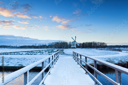 bridge to windmill in snowy winter © Olha Rohulya