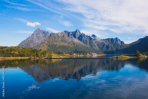 Classic norwegian scandinavian summer landscape with mountains  fjord  lake and a church  with a blue sky  Norway  Lofoten Islands