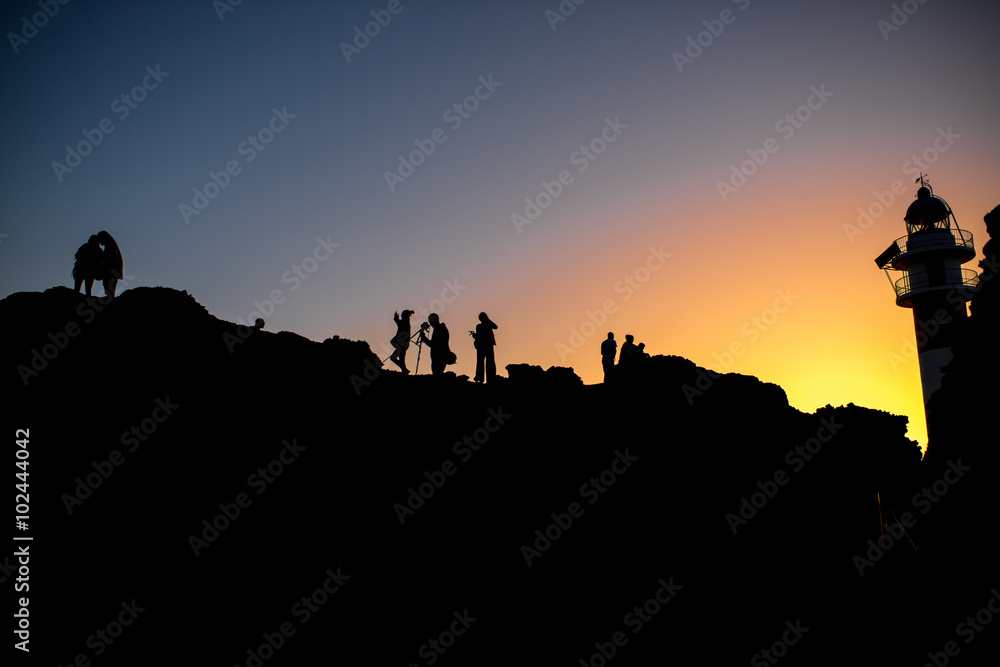 Silhouettes of people near the lighthouse