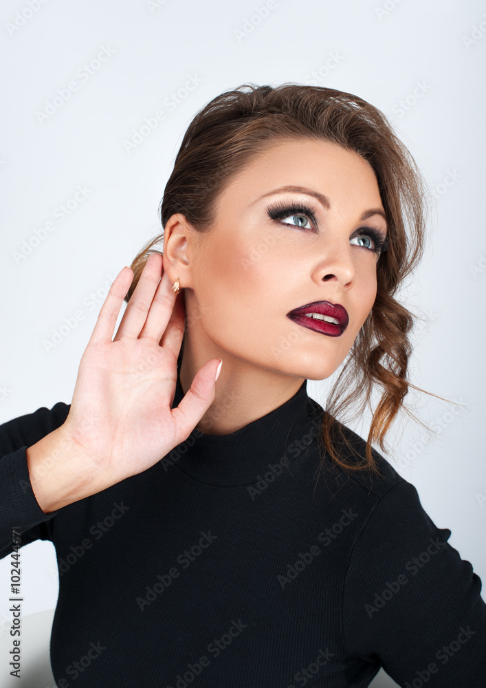 Beautiful girl in black with makeup, hearing a voice, held a han Beautiful girl in black with makeup, hearing a voice, held a han