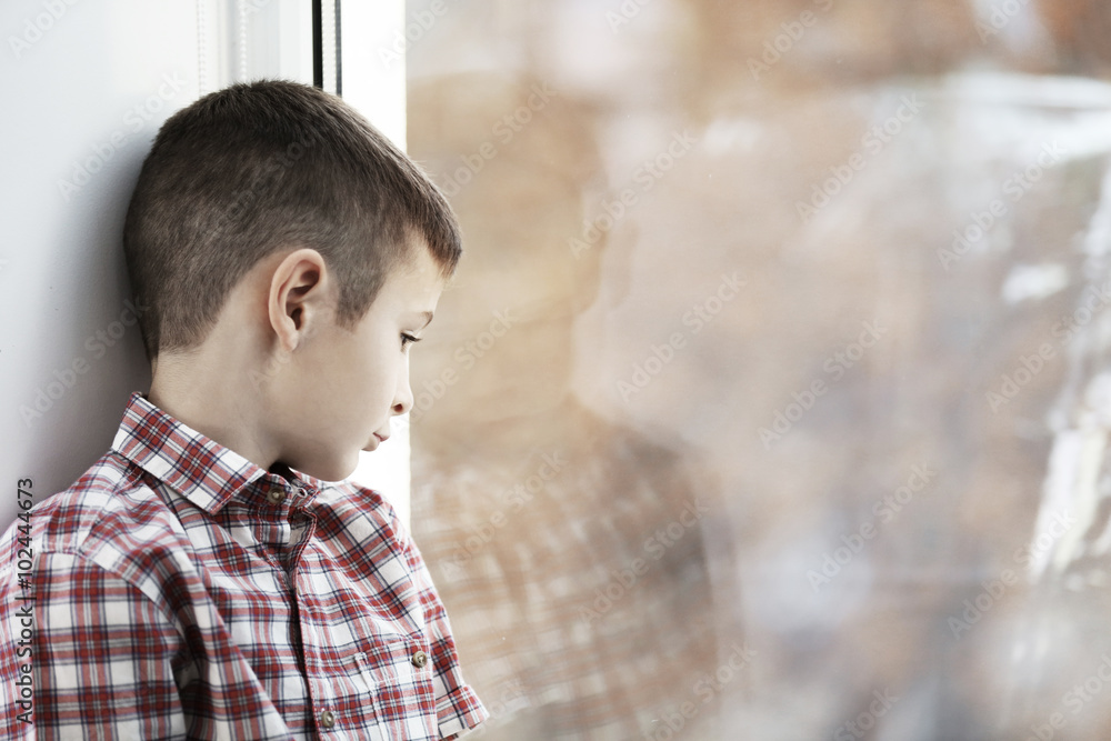 Sad boy sitting near window