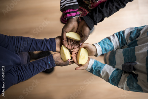 Φωτογραφία Three kids of mixed races each holding a piece of apple in the p