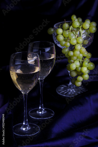 Glasses of wine and grapes on a dark background